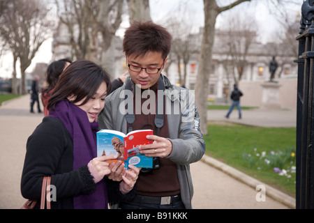 Oriental asiatique couple de touristes dans 20s / 30s visite à Londres, la consultation d'un guide à l'extérieur du Royal Naval College Greenwich Banque D'Images