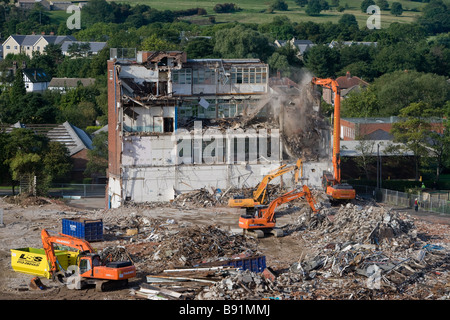 Vue en hauteur du site de démolition (coque d'usine vide, pelles hydrauliques à chenilles lourdes travaillant et démolissant des bâtiments, piles de gravats) - Guiseley, Angleterre, Royaume-Uni. Banque D'Images