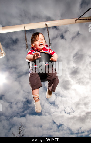 Bébé de 9 mois, se balançant dans un parc. Banque D'Images