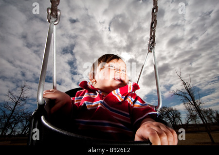 Bébé de 9 mois, se balançant dans un parc. Banque D'Images