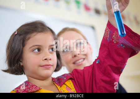 Girl l'inspection d'un tube à essai dans une salle de classe Dubaï Émirats Arabes Unis Banque D'Images