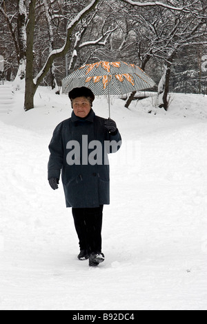 Femme d'âge moyen de transport de marcher dans la neige un parapluie à Prospect Park Brooklyn New York Banque D'Images