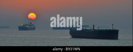 Sunset Haze & Shipping, y compris vraquiers à vide et pétroliers ancrage côtier eau Fujairah port de soutage Golfe d'Oman près du détroit d'Ormuz Banque D'Images