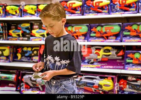 Contrôler son allocation de l'argent avec soin une 10 year old boy se prépare à faire un achat dans un magasin jouets Banque D'Images