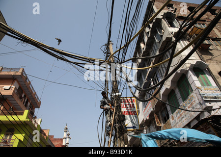 Un électricien répare les câbles sur un poteau dans la rue dans la vieille ville de Delhi, Inde. Banque D'Images