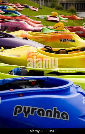 Des kayaks aux couleurs vives sont alignés le long de la rive du fleuve au Tees barrage International White Water Centre avec le pont Tees barrage, Royaume-Uni Banque D'Images