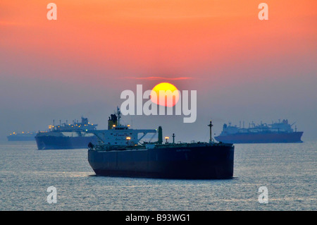 Pétroliers et vraquiers au mouillage côtier dans la brume du coucher du soleil expédition à vide au port de soute de Fujairah des Émirats arabes Unis sur le golfe d'Oman près du détroit d'Ormuz Banque D'Images