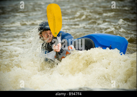 Kayakiste caucasien avec kayak partiellement immergé dans l'eau blanche au Tees barrage International White Water Centre. ROYAUME-UNI Banque D'Images