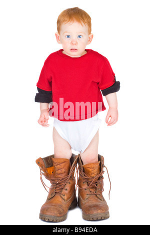 Bébé garçon debout dans une paire de bottes de travail adultes Banque D'Images