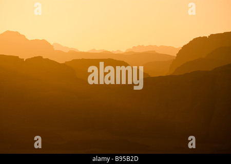 Lointaines montagnes éclairées par le soleil couchant dans le désert de Wadi Rum Jordanie réservation Banque D'Images