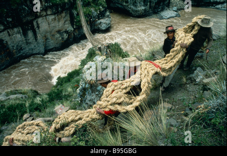 La Gorge de la rivière Apurimac, PÉROU Chumbivilcas Hills hommes portant des cordes d'herbe épaisse pour câbles principaux pour construire le pont de corde sur l'eau Banque D'Images