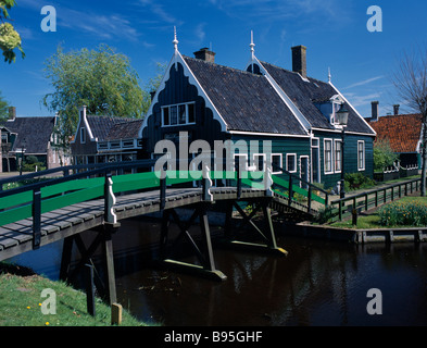 Pays-bas, Noord Holland, Zaanse Schans. L'ensemble de la passerelle menant à la rivière verte typique maison en bois peint dans le village. Banque D'Images