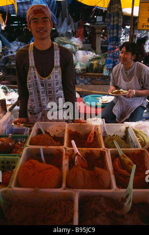 Nord Thaïlande Chiang Mai marché alimentaire de gros vendeur mâle derrière la vente de décrochage sélection de pâtes de cari affiché dans des bols Banque D'Images