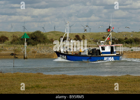 Bateau de pêche revient à Rye Harbour via canal par réserve naturelle. wind farm sur horizon Banque D'Images