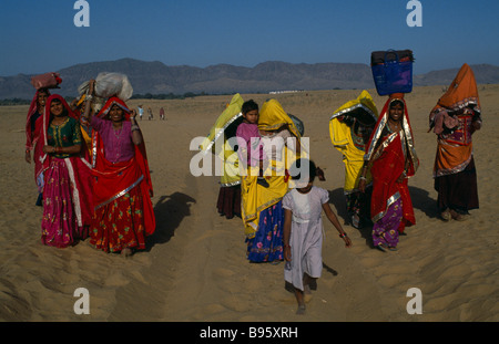 Inde Rajasthan Pushkar Rajasthan habillés de couleurs vives les femmes et les enfants transportant des charges sur leur tête. Banque D'Images