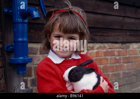 Andover Hampshire ANGLETERRE Jeune fille tenant un lapin noir et blanc à Finkley Down Farm Banque D'Images