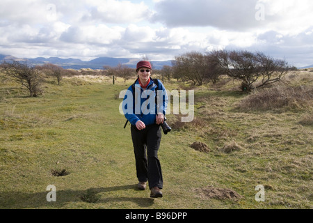 Le Nord du Pays de Galles d'Anglesey Newborough mars une femme marche le long d'un sentier balisé dans la réserve naturelle nationale Newborough Warren Banque D'Images