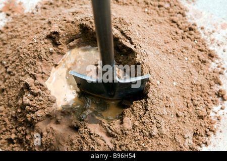 Le sable et le ciment de Portland ont été mélangés et l'eau est ajoutée dans un trou au centre et mixte du centre vers l'intérieur Banque D'Images