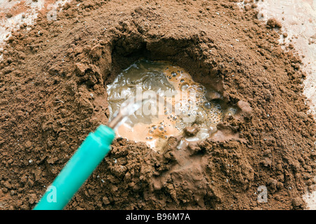 Le sable et le ciment de Portland ont été mélangés et l'eau est ajoutée dans un trou dans le centre Banque D'Images