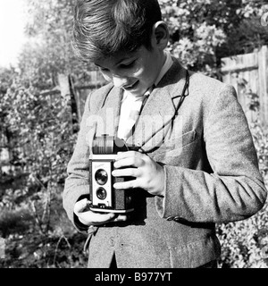 1950s, historique, regardant vers le bas son viseur, un adolescent dans un jardin utilisant un appareil photo Kodak Brownie reflex Box pour prendre une photo, Angleterre, Royaume-Uni. Banque D'Images