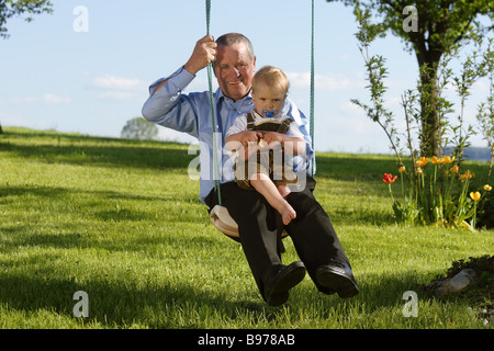 Grand-père avec un enfant sur une balançoire Banque D'Images