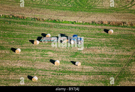 Vue aérienne d'un tracteur et remorque à plateau. Bottes de paille dans un champ. Le Hampshire. UK. Banque D'Images