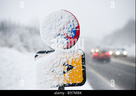 La signalisation routière couvert de neige avec le trafic passant par les hivers sur un jour en Angleterre Banque D'Images
