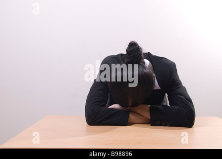 Business Woman sat in office head in hands Banque D'Images