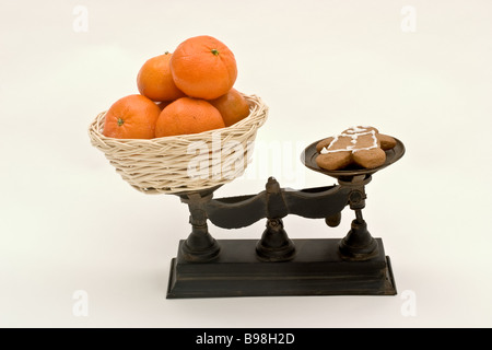 Balance avec un panier d'oranges d'un côté et a gingerbread cookie sur l'autre Banque D'Images