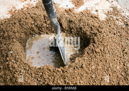 Le sable et le ciment de Portland ont été mélangés et l'eau est ajoutée dans un trou au centre et mixte du centre vers l'intérieur Banque D'Images