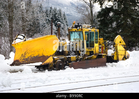 En train chasse-neige neige sous des nuages sombres Banque D'Images