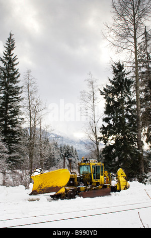 En train chasse-neige neige sous des nuages sombres Banque D'Images