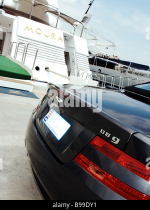 Une Aston Martin DB9 bleue garée à côté de la Dame Moura super yacht de luxe amarrés dans le port de Monaco Monte Carlo. Banque D'Images