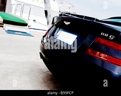 Une Aston Martin DB9 bleue garée à côté de la Dame Moura super yacht de luxe amarrés dans le port de Monaco Monte Carlo. Banque D'Images