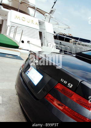 Une Aston Martin DB9 bleue garée à côté de la Dame Moura super yacht de luxe amarrés dans le port de Monaco Monte Carlo Banque D'Images