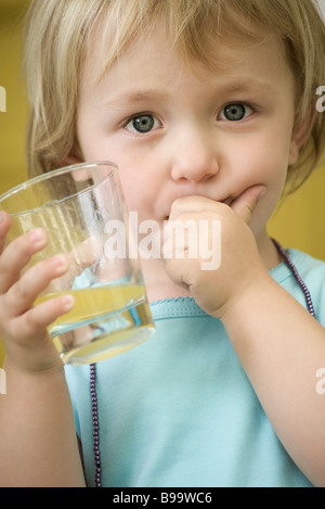 Girl holding verre de jus, couvrant la bouche avec une main Banque D'Images