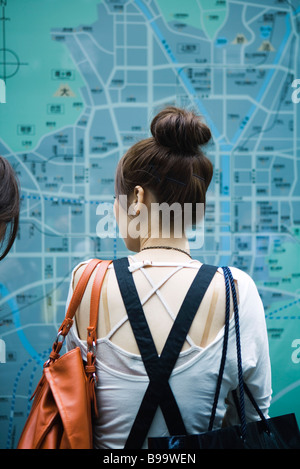 Femme regardant grande carte sur le mur, vue arrière Banque D'Images