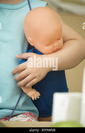 Child holding baby doll, cropped view Banque D'Images