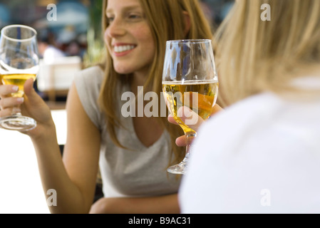 Les jeunes femmes de boire une bière at sidewalk cafe, cropped Banque D'Images