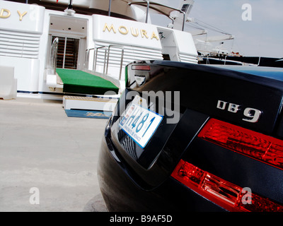 Une Aston Martin DB9 bleue garée à côté de la Dame Moura super yacht de luxe amarrés dans le port de Monaco Monte Carlo. Banque D'Images