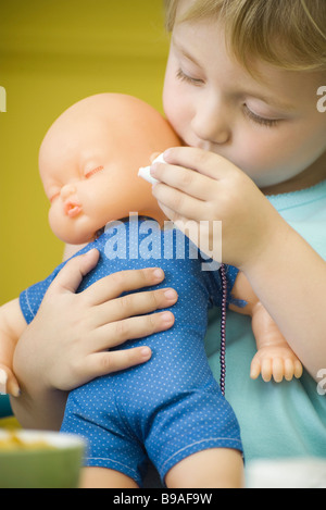 Little girl holding baby doll, close-up Banque D'Images