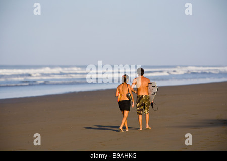 Jeune couple en train de marcher le long de la plage de golden Morning sun à Playa dominical à Puntarenas, Costa Rica. Banque D'Images