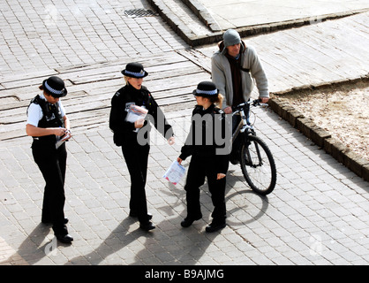 Un cycliste passe trois agents de soutien communautaire de police PCSO sur le front de mer de Brighton au Royaume-Uni Banque D'Images