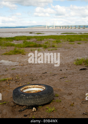 Roue et pneu de voiture abandonnée sur Severn Beach près de Bristol, Royaume-Uni. Deuxième Severn Crossing Bridge est à distance. Banque D'Images