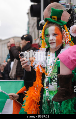 Jeune fille habillé en costume leprochaun et le visage peint en vert, blanc et orange, est titulaire d'une caméra vidéo. St Patricks day parade. Banque D'Images