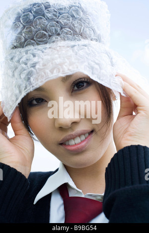 Jeune femme portant chapeau fait de papier bulle, portrait Banque D'Images