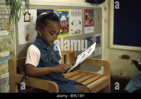 Fille afro-antillaise reading in library Banque D'Images