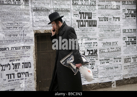 Le juif orthodoxe passe devant les affiches grand format Pashkvilim qui servent d'annonces communautaires dans le quartier de MEA Shearim Haredi à Jérusalem en Israël Banque D'Images