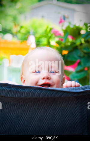 Blue Eyed baby boy playing peek a boo on chair Banque D'Images