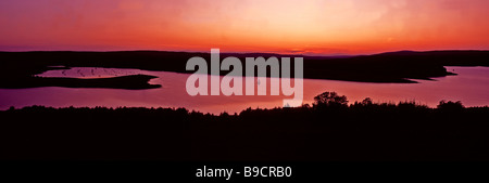 Un magnifique coucher de soleil avec un bateau à voile sur l'eau dans la forêt de Kielder Kielder Northumberland Banque D'Images